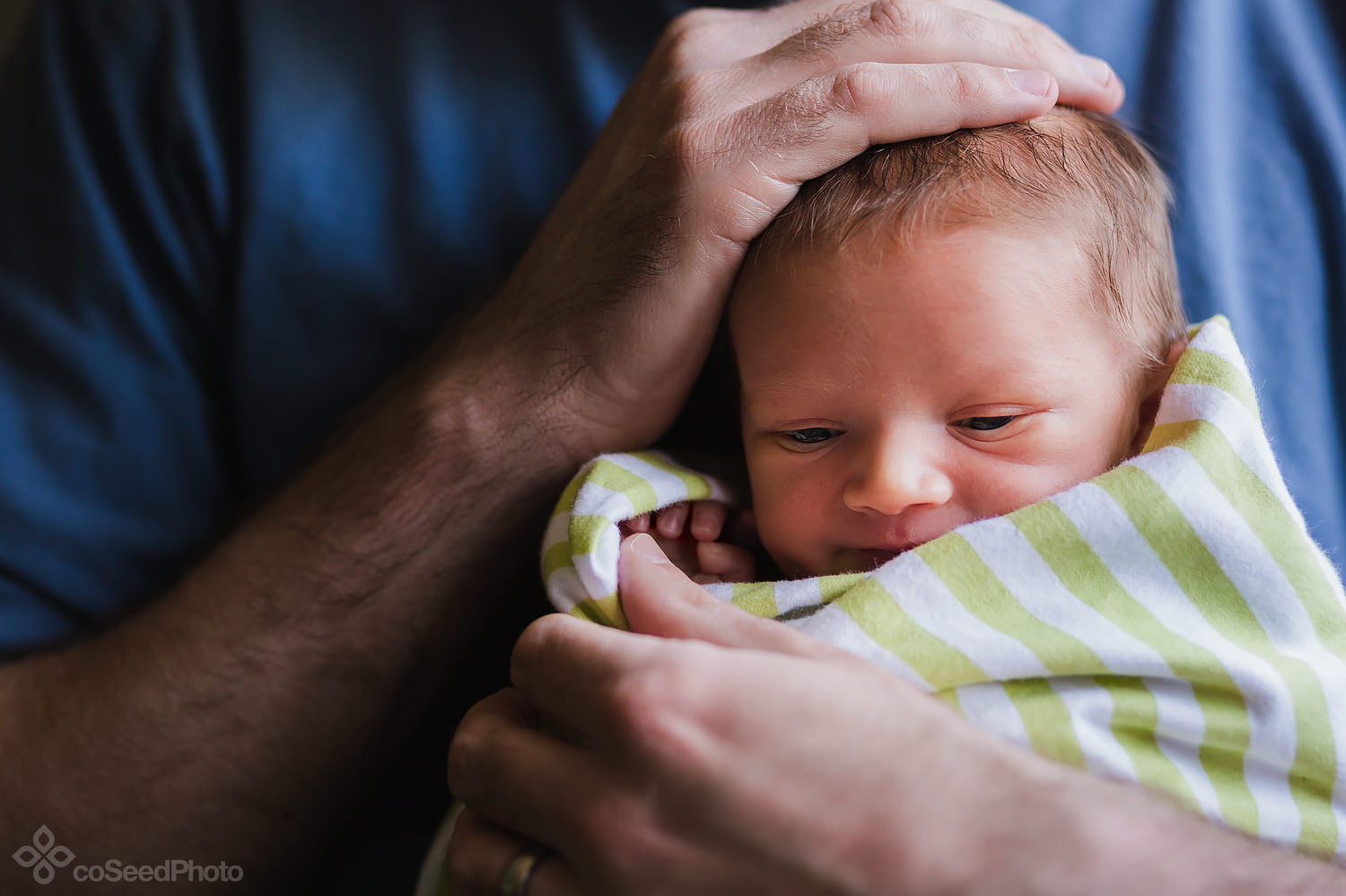 Newborn Declan with his dad's hand resting atop his head.