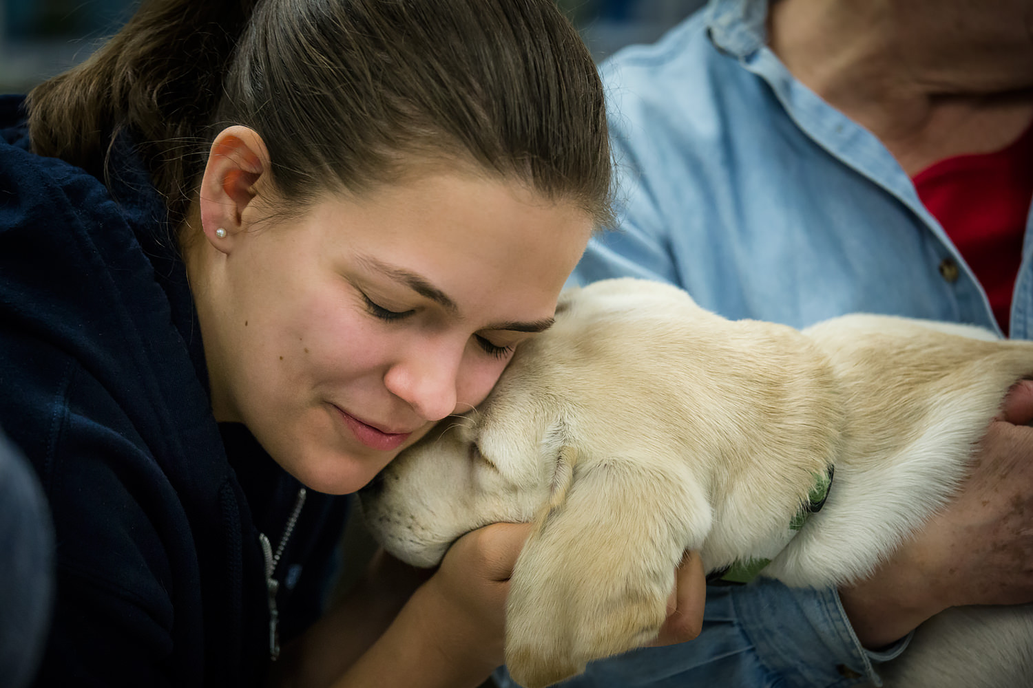 Guiding Eyes volunteer cheek to cheek with yellow lab.